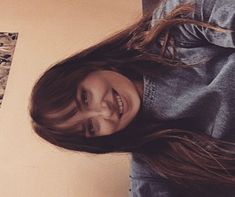 a woman with long brown hair smiling at the camera