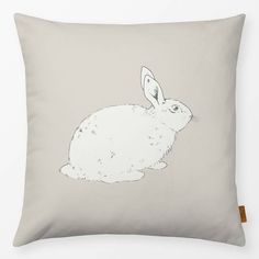 a grey pillow with a white rabbit drawn on it