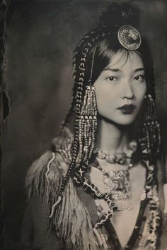 an old black and white photo of a woman with braids on her head, wearing jewelry