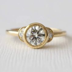 a yellow gold engagement ring with two diamonds on it's sides and the center stone in