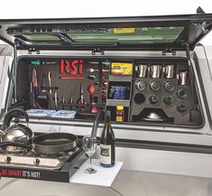 an open car trunk filled with tools and cooking utensils on top of a table