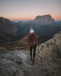 a woman walking up the side of a mountain with her hands in her pockets and headband