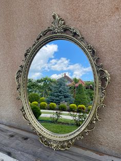 a mirror on the side of a building with trees in the background and clouds in the sky