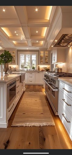 a large kitchen with white cabinets and wood flooring, along with a rug on the floor