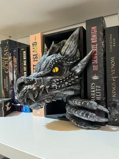 a book shelf with books and a dragon head on it