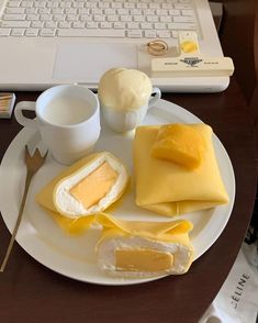 a white plate topped with food next to a cup of coffee and a laptop computer