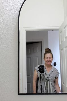 a woman standing in front of a mirror holding a camera