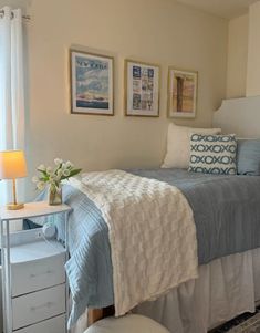 a bed sitting in a bedroom next to a window with pictures on the wall above it