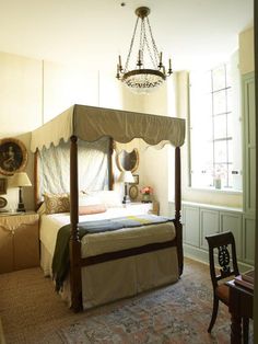 a bedroom with a four poster bed, chandelier and table in the corner