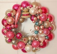 a pink and gold christmas ornament wreath hanging on a door