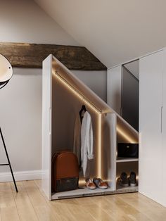 an open closet with clothes and shoes on the floor, next to a tripod light