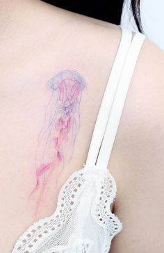 the back of a woman's shoulder with a jellyfish tattoo on it