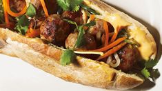 a meatball sandwich with carrots, onions and cilantro on a white plate