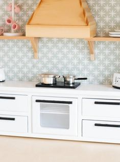 a toy stove with pots and pans on top of it in front of a wallpapered background