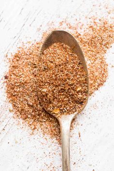 a spoon filled with spices on top of a white table