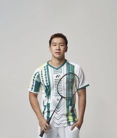 a young man holding a tennis racquet on top of a white floor next to a gray wall