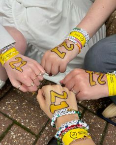 two people holding hands with numbers painted on their arms and bracelets in the shape of smiley faces