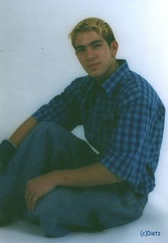 a young man sitting on the ground with his legs crossed