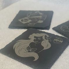 three black coasters with silver designs on them