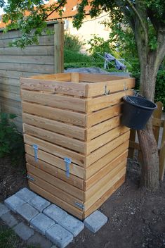 a large wooden box sitting in the middle of a yard next to a small tree