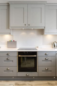 a kitchen with gray cabinets and white counter tops