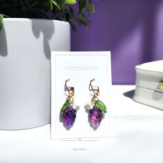 a pair of earrings sitting on top of a white table next to a potted plant