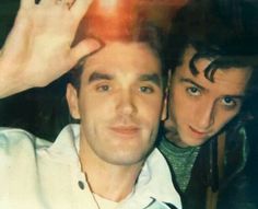 two young men posing for the camera with one holding his hand up to their head