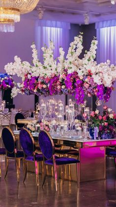 an elegant table with purple and white flowers in tall vases on the centerpiece