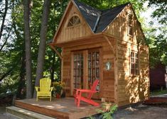 a small wooden cabin in the woods with two yellow chairs and a red lawn chair