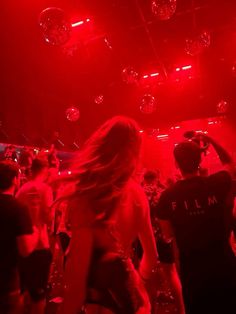 a group of people dancing in a club with red lights and disco balls hanging from the ceiling