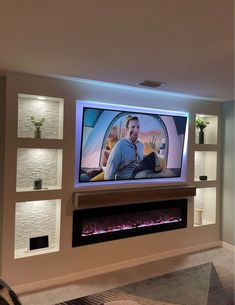 a man sitting in front of a tv on top of a wall next to a fire place