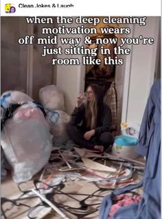 a woman sitting on the floor in front of a pile of clothes and other items