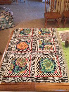 a table with a quilt on top of it next to a chair and coffee table