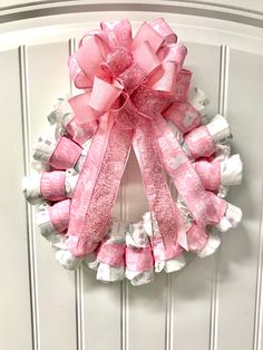 a pink and white wreath hanging on the front door with candy wrappers around it