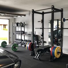 a man is working out in the garage with his car parked next to him,