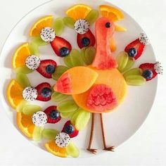 a white plate topped with fruit and a turkey cut out of it's body