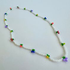 a white beaded necklace with multicolored beads and flowers hanging from it's end