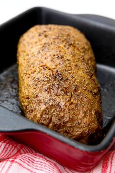 a piece of meat in a red pan on top of a white and red towel