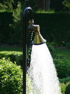 a sprinkle is spraying water from a hose in the garden, with bushes and shrubs behind it