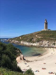 people are laying on the beach and in the water next to a tower with a clock