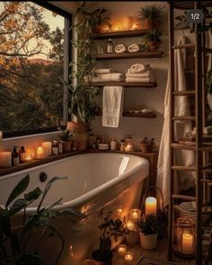 a bathroom with candles and plants on the floor next to a bathtub in front of a window