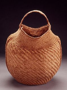 an old woven basket is sitting on the floor in front of a black background,