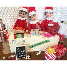 two elfs sitting on top of a table with gifts