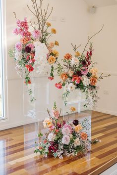 two clear vases filled with flowers on top of a wooden table