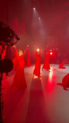 a group of women in red dresses dancing on stage