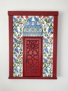 a red door with an intricate design on it's side and the top panel painted white