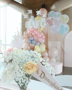 a vase filled with flowers sitting on top of a table next to balloons and signs