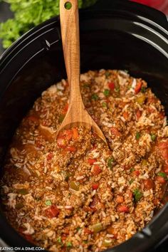 a wooden spoon in a slow cooker filled with rice and vegetables