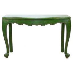 an antique green console table with scalloped legs