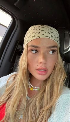 a woman sitting in the back seat of a car wearing a headband and looking at the camera